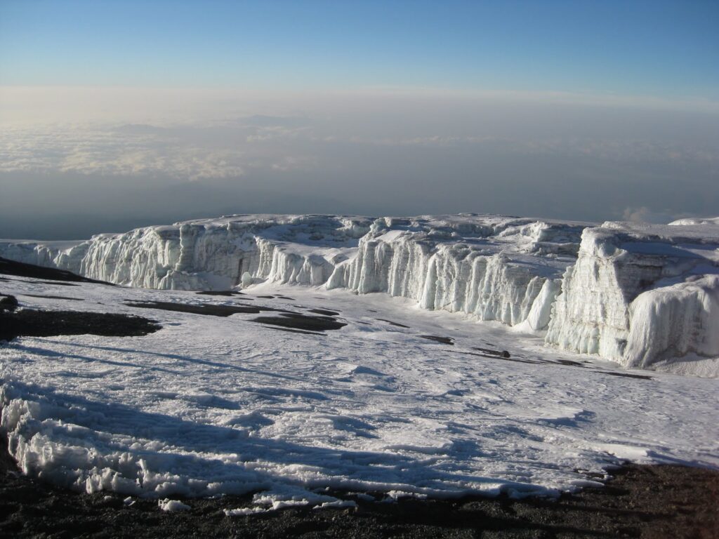 Climbers approaching Uhuru Peak summit of Mount Kilimanjaro at sunrise with glaciers and crater rim visible Tanzania