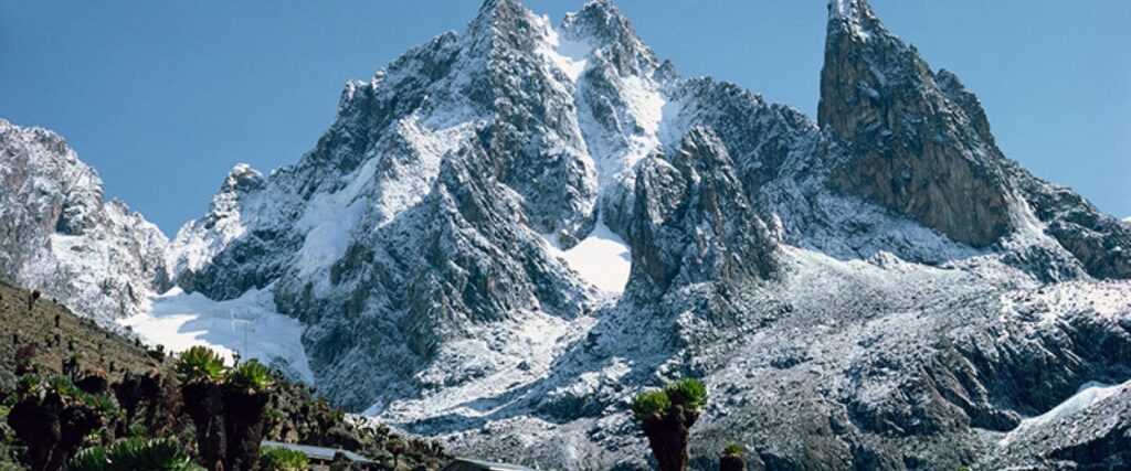 "Mount Kenya jagged peaks with glaciers against blue sky viewed from moorland"